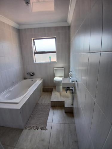a bathroom with a tub and a toilet and a sink at Jate Guest House in Maseru
