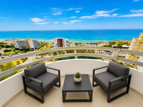 a balcony with two chairs and a table and the ocean at Luxury Ocean View Apartments I Sunset Terrace I Pool I 200m to Praia dos Três Castelos in Portimão