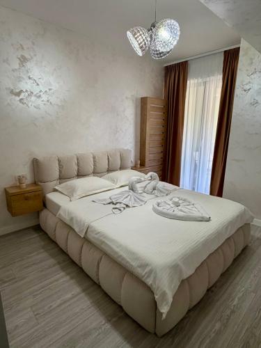 a bedroom with a large white bed with a chandelier at ND Central Apartment in Râmnicu Vâlcea