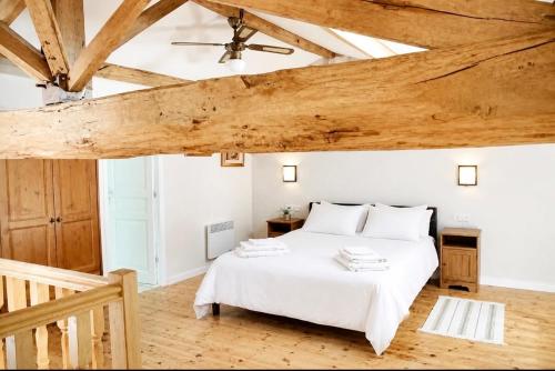 a bedroom with a white bed and wooden ceilings at Gites de Source in Châtenet