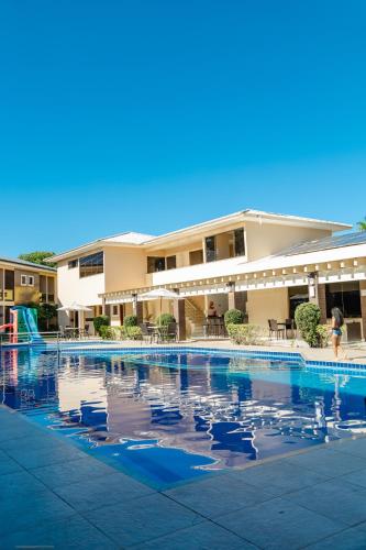 a person walking by a swimming pool with birds in the water at Safira Praia Hotel in Porto Seguro