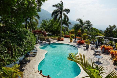 a swimming pool with palm trees and mountains in the background at Hotel Montana in Petionville