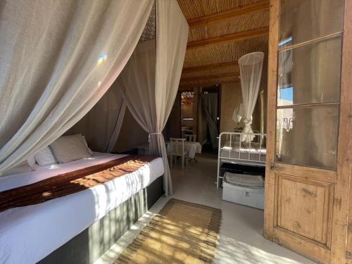 a bedroom with a bed and a window with curtains at Strooi Kooi - Unique Strawbale Cottage in Calitzdorp