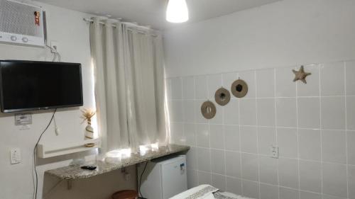 a bathroom with a toilet and a tv on the wall at POUSADA MEGA in Marataizes