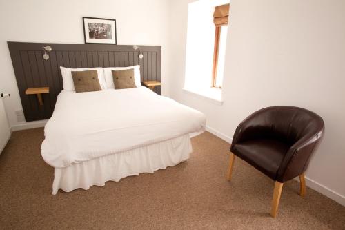 a bedroom with a white bed and a chair at The Arch Inn in Ullapool
