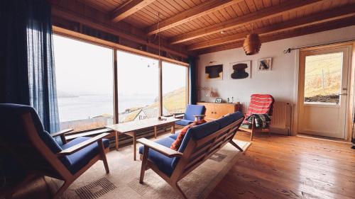 a living room with chairs and a table and windows at Idyllic Vacation Home with a Breathtaking View in Bøur