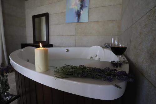 a white bath tub with a candle and a glass of wine at Hacienda 888 in Ḑahr al Baydar