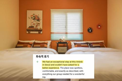 two beds in a room with orange walls at 101STAYㅣFamily-FriendlyㅣStn 1minㅣ2BR 3BedsㅣPrivate Houseㅣ6 GuestsㅣPrivate Yard #DDP #경복궁 #남산 #명동 #홍대 #성수 in Seoul