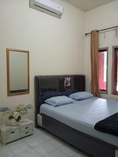 a bedroom with a bed and a mirror and a window at Thian Homestay in Batukaras