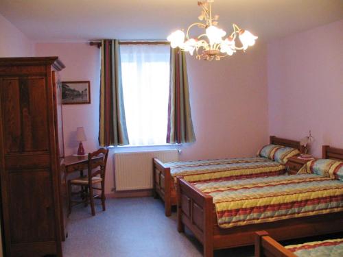 a bedroom with two beds and a desk and a window at La ferme de la fontaine in Douzy