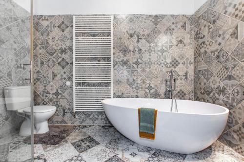 a bathroom with a white tub and a toilet at Resort Biskupský Dvůr in Višňová