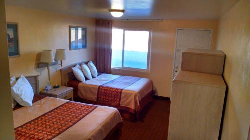 um quarto de hotel com duas camas e uma janela em White Sands Motel em Alamogordo