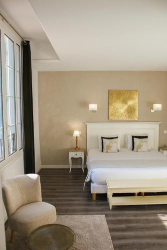 a bedroom with a large white bed and a chair at Hôtel Beau Site - Cap d'Antibes in Antibes