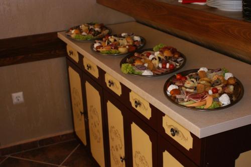 three plates of food on a counter with plates of food at Pensiunea Normandia in Timişoara