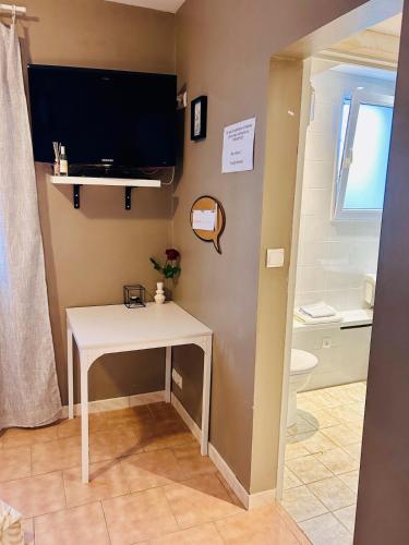 a bathroom with a white table and a tv on the wall at Studio proche RN145 Chez Greg in Saint-Sulpice-le-Guérétois