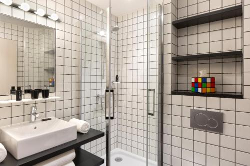 La salle de bains est pourvue de carrelage blanc, d'un lavabo et d'une douche. dans l'établissement RockyPop Chamonix - Les Houches, aux Houches