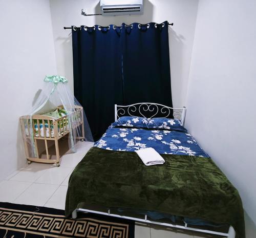 a bedroom with a bed with a blue curtain at Cozystayz NuNa in Sitiawan