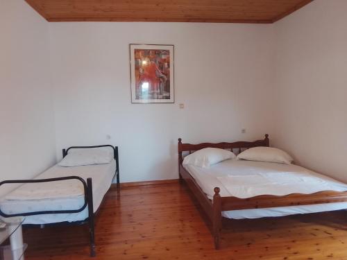 two beds in a room with white walls and wooden floors at Relaxhouse in Himare