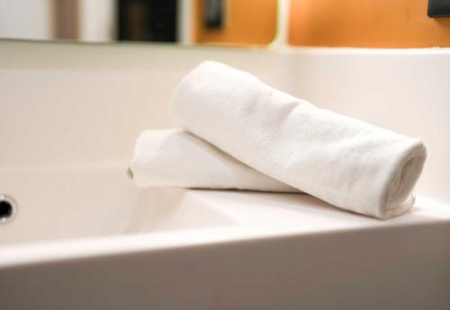 a stack of white towels sitting on a bathroom sink at B&B HOTEL Amiens Sud in Amiens