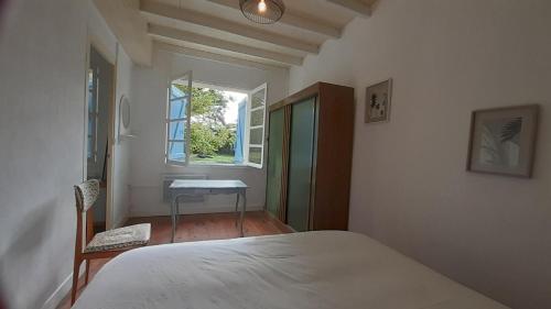 a bedroom with a bed and a desk and a window at Le gîte du château in Monget