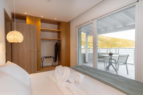 a bedroom with a bed and a balcony with a table at eu Τhea Apt Samos - Sandy Beach & Amazing View in Psili Ammos