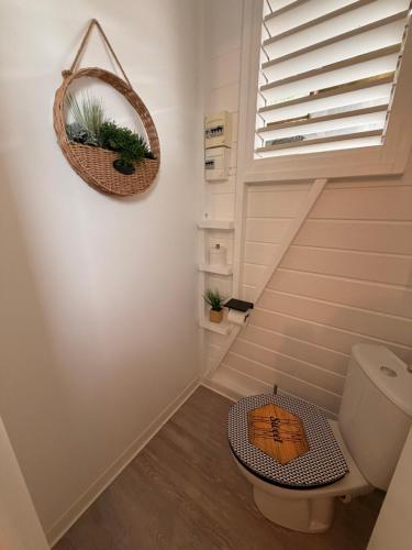 a bathroom with a toilet and a basket with plants at Bungalow la tipik in Saint-François