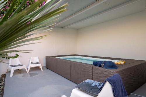 a hot tub in a room with two chairs and a plant at Villa Victoris Beachfront Luxury Villa with Heated Spa Pool Podstrana in Podstrana