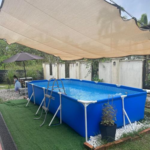 a blue swimming pool with a large tent over it at Yasmeen pool cottage in Temerloh