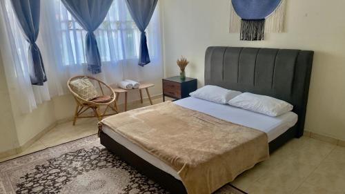a bedroom with a bed and a chair and windows at Yasmeen pool cottage in Temerloh