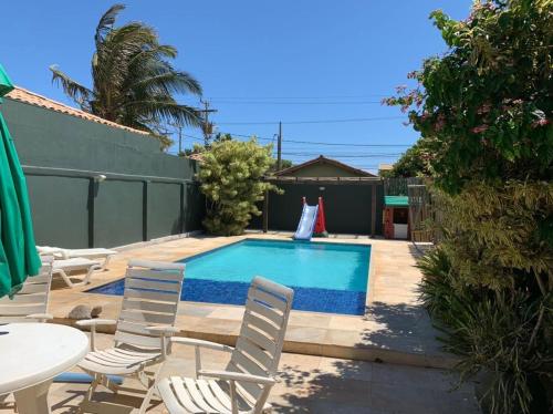 ein Garten mit Pool, Stühlen und einem Tisch in der Unterkunft Casa do Ventoo in Búzios