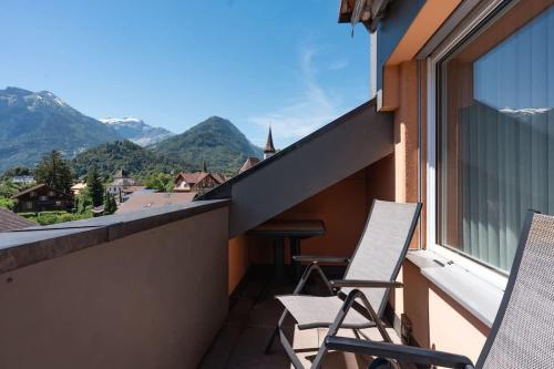 two chairs on a balcony with a view of mountains at Charming Alpine Apt with View 5min to Interlaken Ost in Interlaken