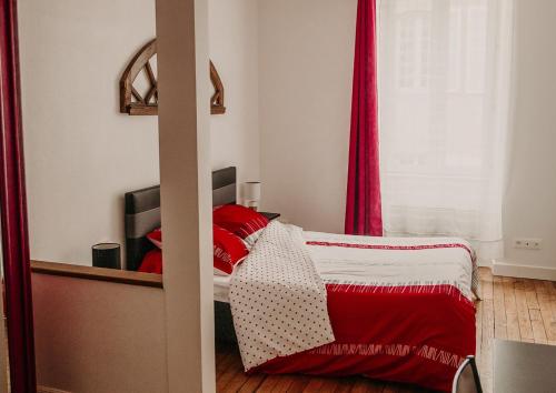 a bedroom with a bed with red sheets and a window at Le Classique in Saint-Sulpice-le-Guérétois