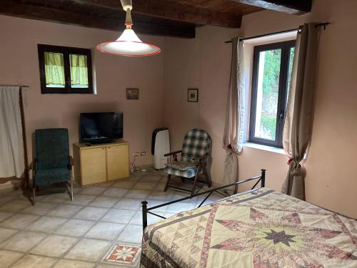 a bedroom with a bed and two chairs and a television at Palazzo giallo, appartamento nel centro storico nel cuore del Pollino in Morano Calabro