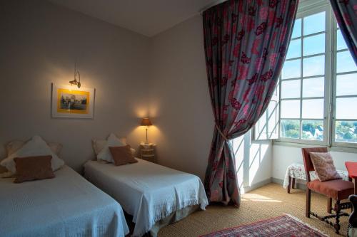 a bedroom with two beds and a large window at Chateau de Durtal in Durtal