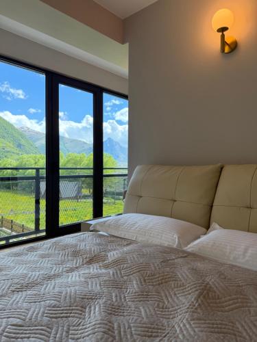 a bedroom with a bed and a large window at Oli Home in Kazbegi