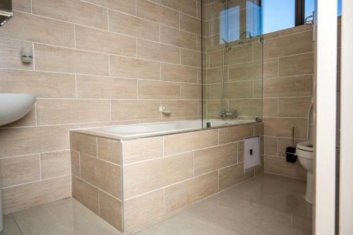 a bathroom with a tub and a toilet at Sycamon Suites in Jwaneng