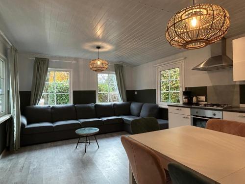 a living room with a couch and a table at Boslodge 7 personen in Tiendeveen