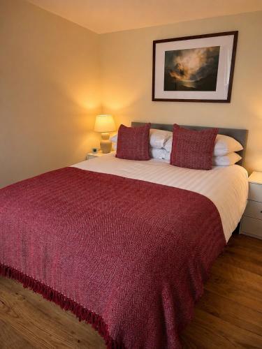 a bedroom with a large bed with a red blanket at Minch View Cabin 2, 1 Earlish in Earlish
