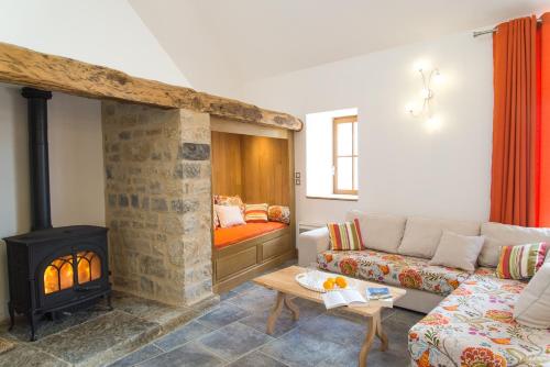 a living room with a couch and a fireplace at L'etable de pierre in Nojaret
