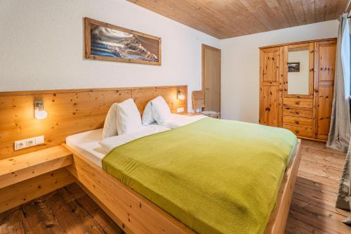 a bedroom with a large bed with a green blanket at Appartements Kaltenbach in Kaltenbach