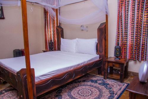 a bedroom with a canopy bed with white sheets at Jumbo Art S Villas in Diani Beach