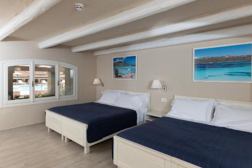 two beds in a room with two windows at Hotel Nibaru in Porto Cervo