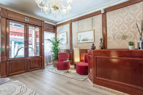 a lobby with red chairs and a table and a chandelier at Hotel Falier in Venice