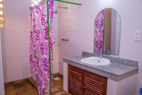a bathroom with a sink and a pink shower curtain at Jumbo Art S Villas in Diani Beach