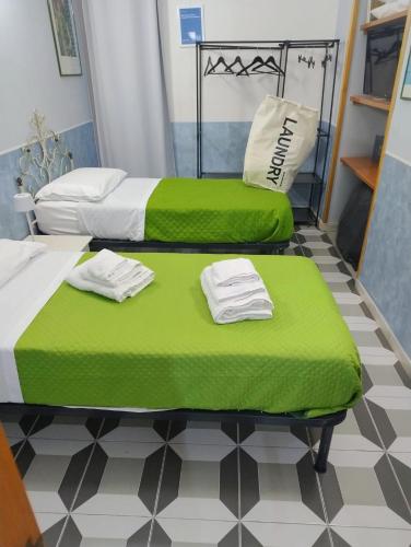 two beds in a room with green sheets and towels at Bell'e Buono vicino aeroporto di Capodichino in Naples