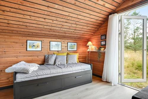 a bed in a wooden room with a window at BV422-Blavand-Hedetoftvej-2 in Blåvand