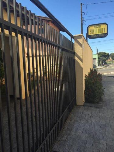 a fence in front of a building with a sign at Pousada Santa Lolla in São Carlos