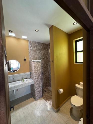 a bathroom with a toilet and a sink and a shower at Casa Colibrí in Zipolite