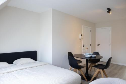 a bedroom with a bed and a table and chairs at Cozy apartment with a great location at "Residentie GAUGUIN" in Nieuwpoort
