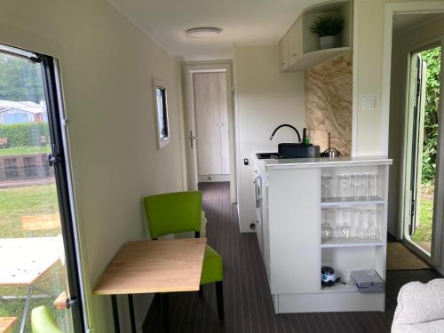 a small kitchen with a table and a green chair at TinyHouse am Stadthafen in Hennigsdorf